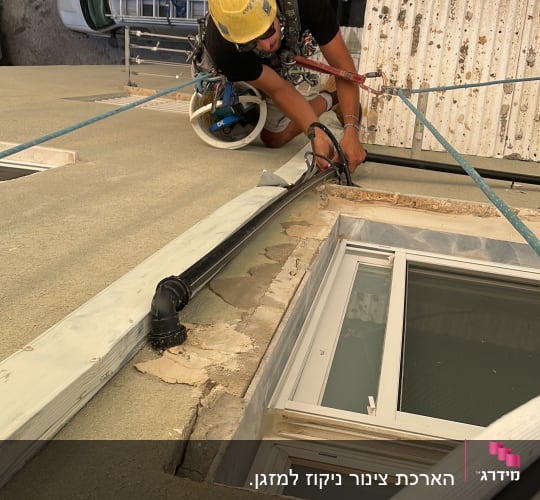 עובד בגובה עם קסדה צהובה מחובר לחבלים